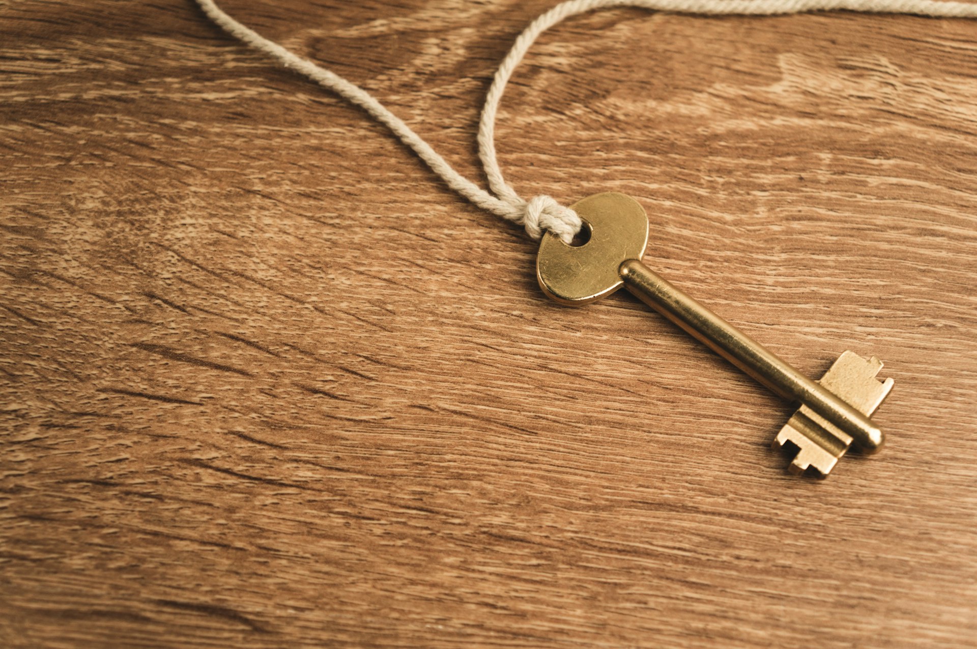 a golden key on a string on a wooden surface